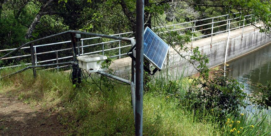 Monitoring station at Searsville Dam showing datalogger and PV panel along trail west of lake.